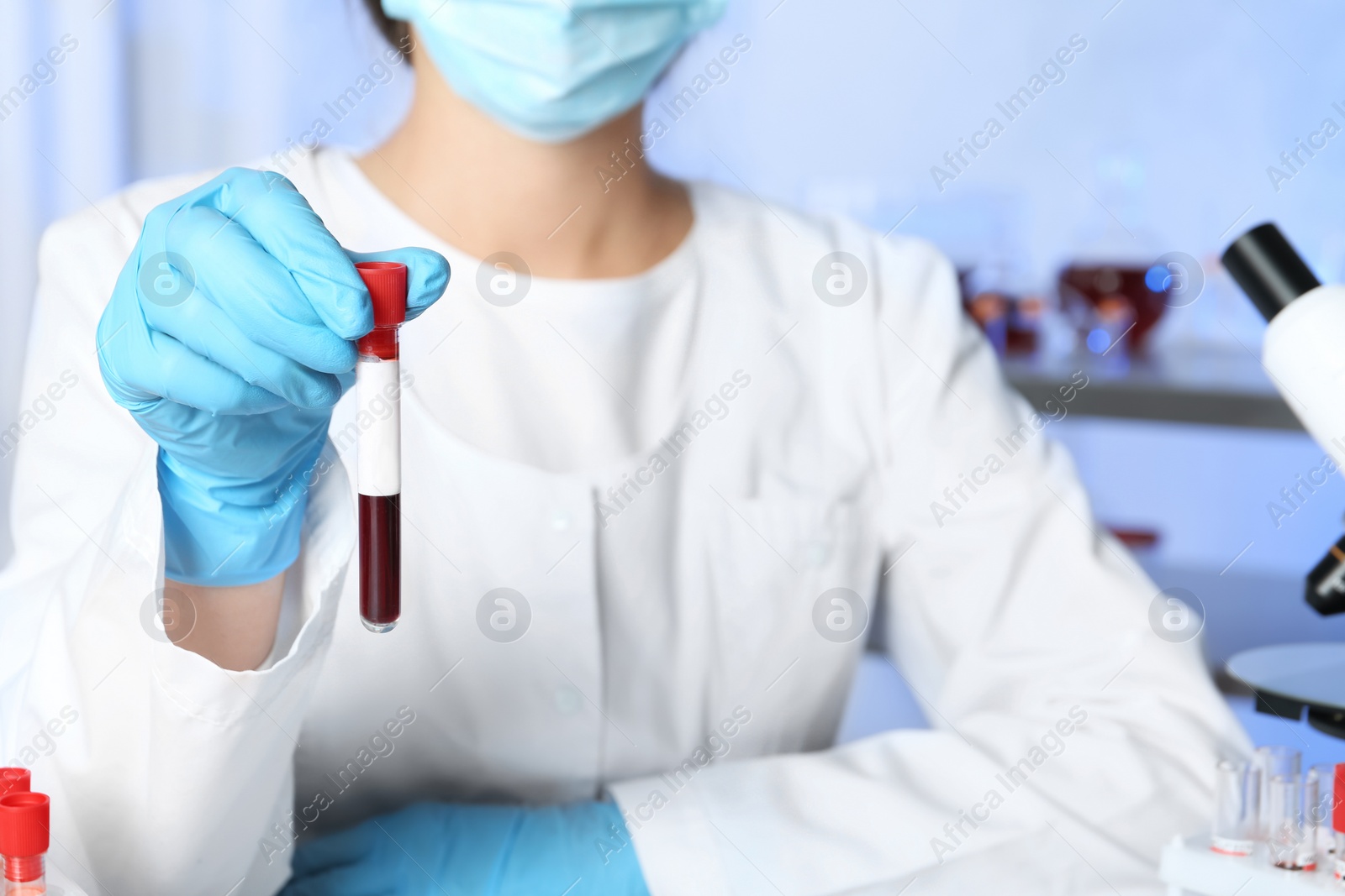 Photo of Laboratory worker holding test tube with blood sample for analysis, closeup