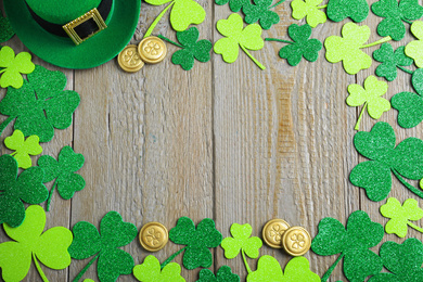 Photo of Frame made of clover leaves and green hat on wooden table, flat lay with space for text. St. Patrick's Day celebration