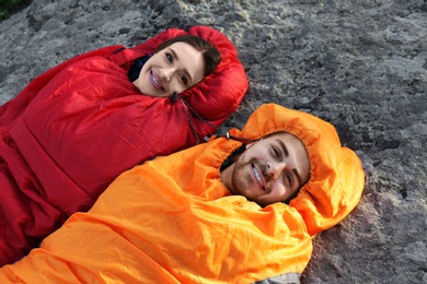 Photo of Happy young couple lying in sleeping bags outdoors