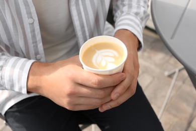 Photo of Coffee to go. Man with paper cup of drink outdoors, closeup