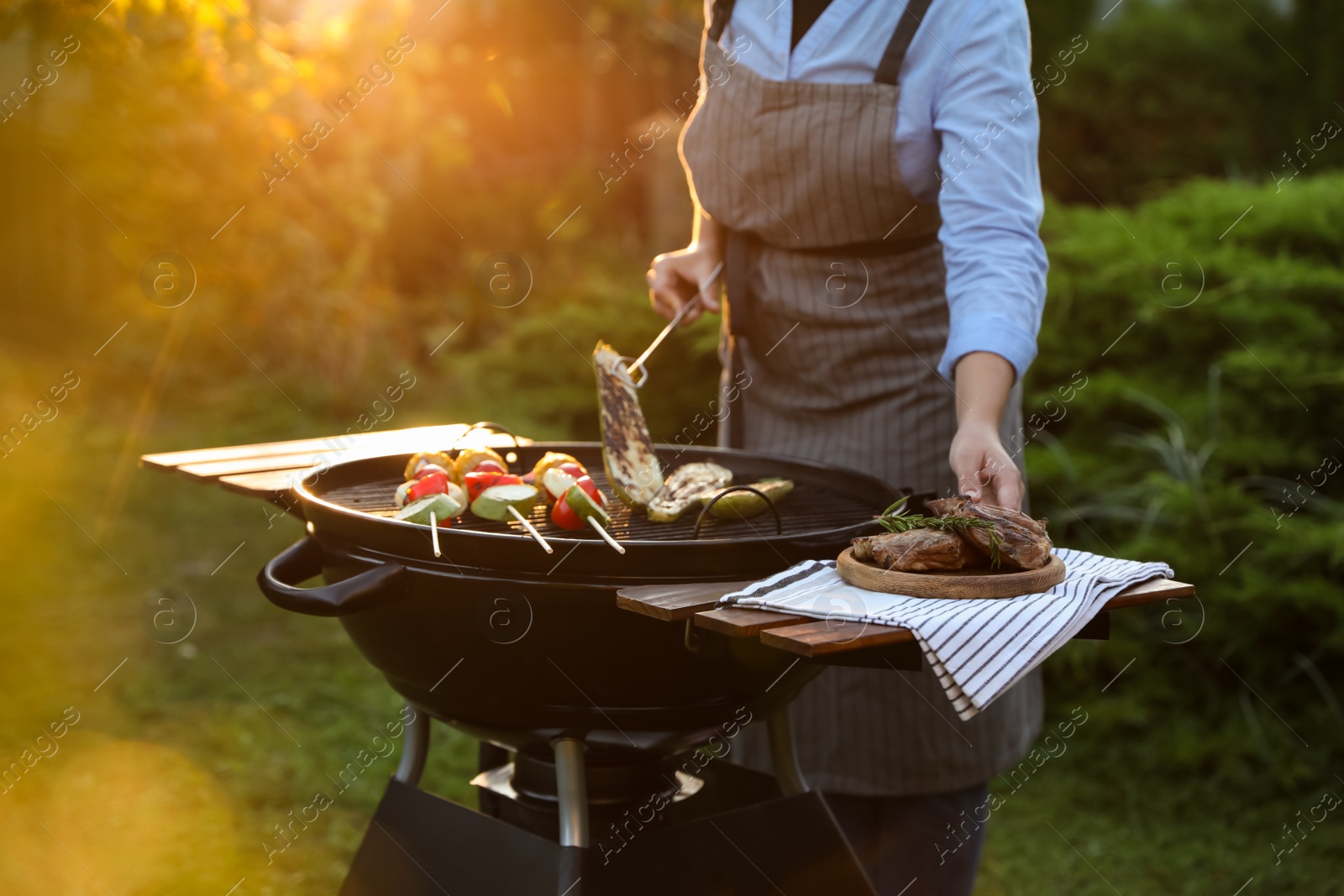 Photo of Woman cooking vegetables on barbecue grill outdoors, closeup