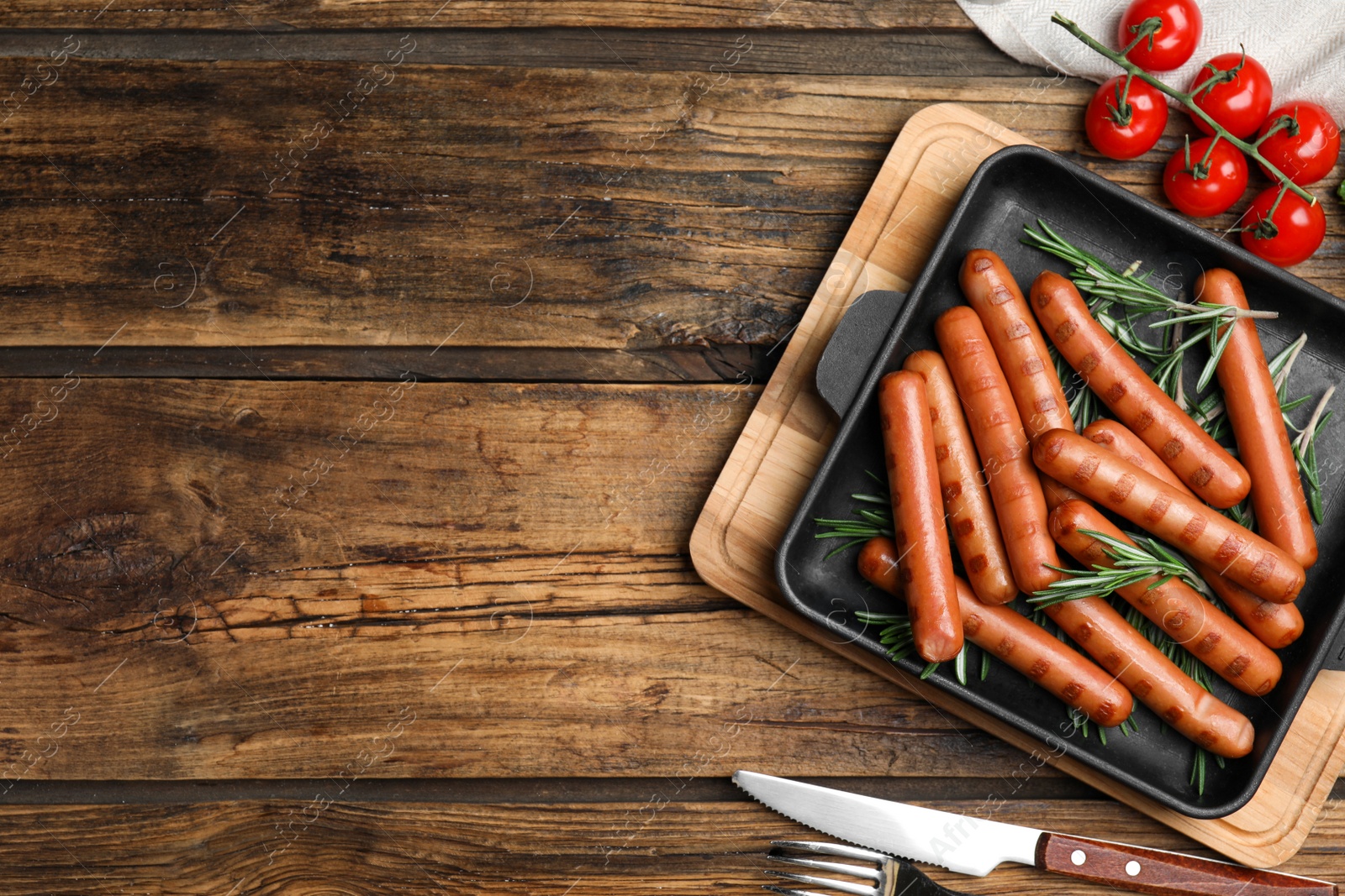 Photo of Tasty grilled sausages served on wooden table, flat lay. Space for text