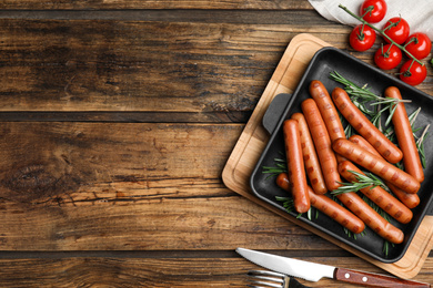 Photo of Tasty grilled sausages served on wooden table, flat lay. Space for text