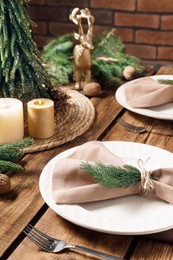 Festive place setting with beautiful dishware, cutlery and fabric napkin for Christmas dinner on wooden table