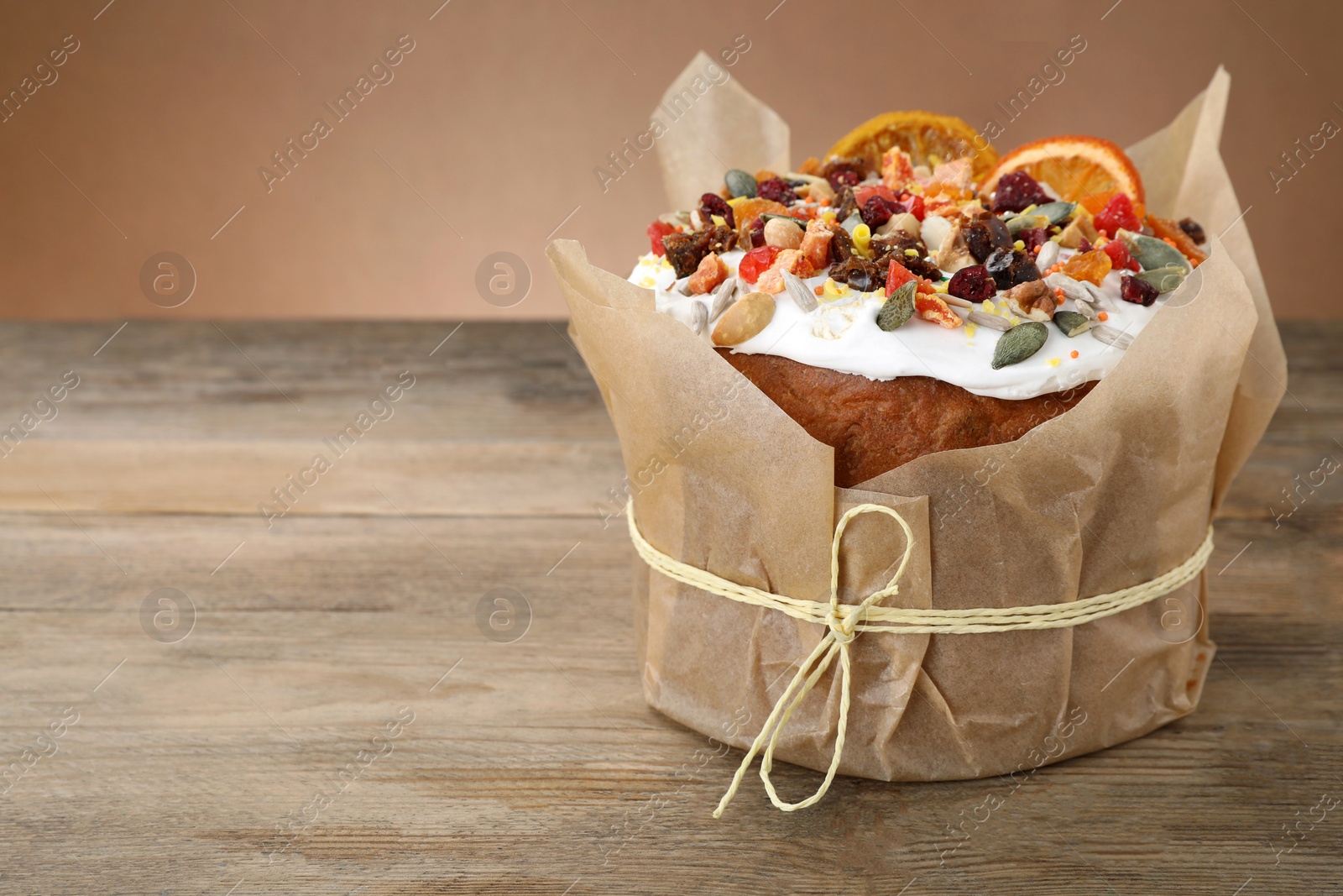 Photo of Traditional Easter cake with dried fruits on wooden table, space for text