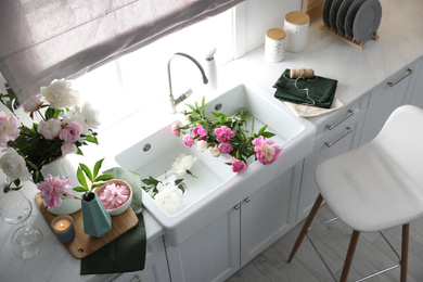 Photo of Beautiful kitchen interior with stylish furniture and fresh peonies