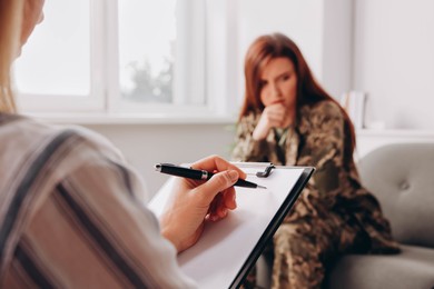 Photo of Psychologist working with military officer in office, focus on hand