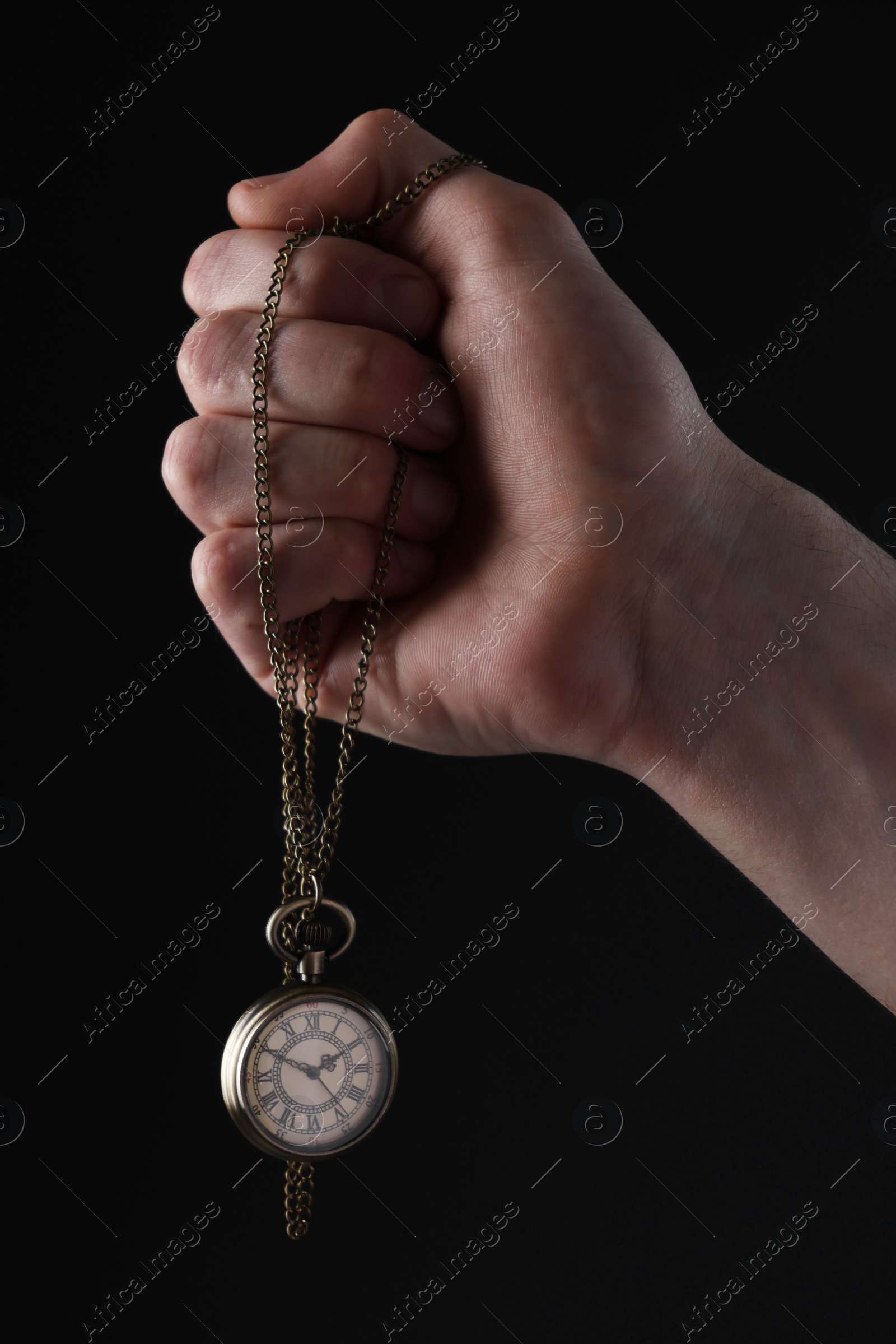 Photo of Man holding chain with elegant pocket watch on black background, closeup