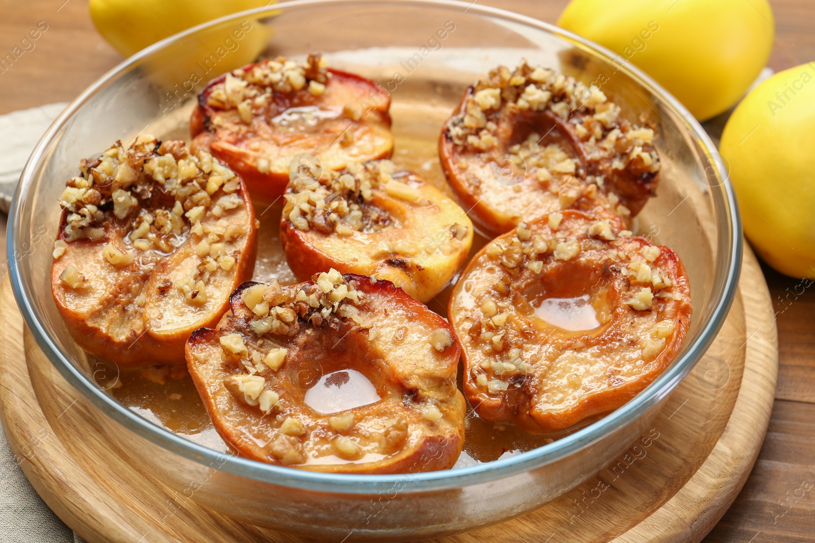 Photo of Tasty baked quinces with walnuts and honey in bowl on wooden table, closeup