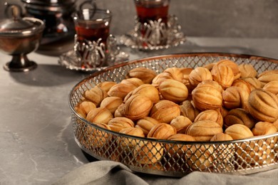 Photo of Delicious walnut shaped cookies and tea on grey table, closeup. Tasty pastry carrying nostalgic home atmosphere