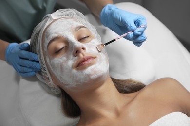 Photo of Cosmetologist applying mask on client's face in spa salon