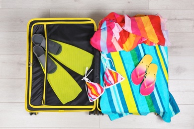 Photo of Packed suitcase for summer vacation on wooden background, top view