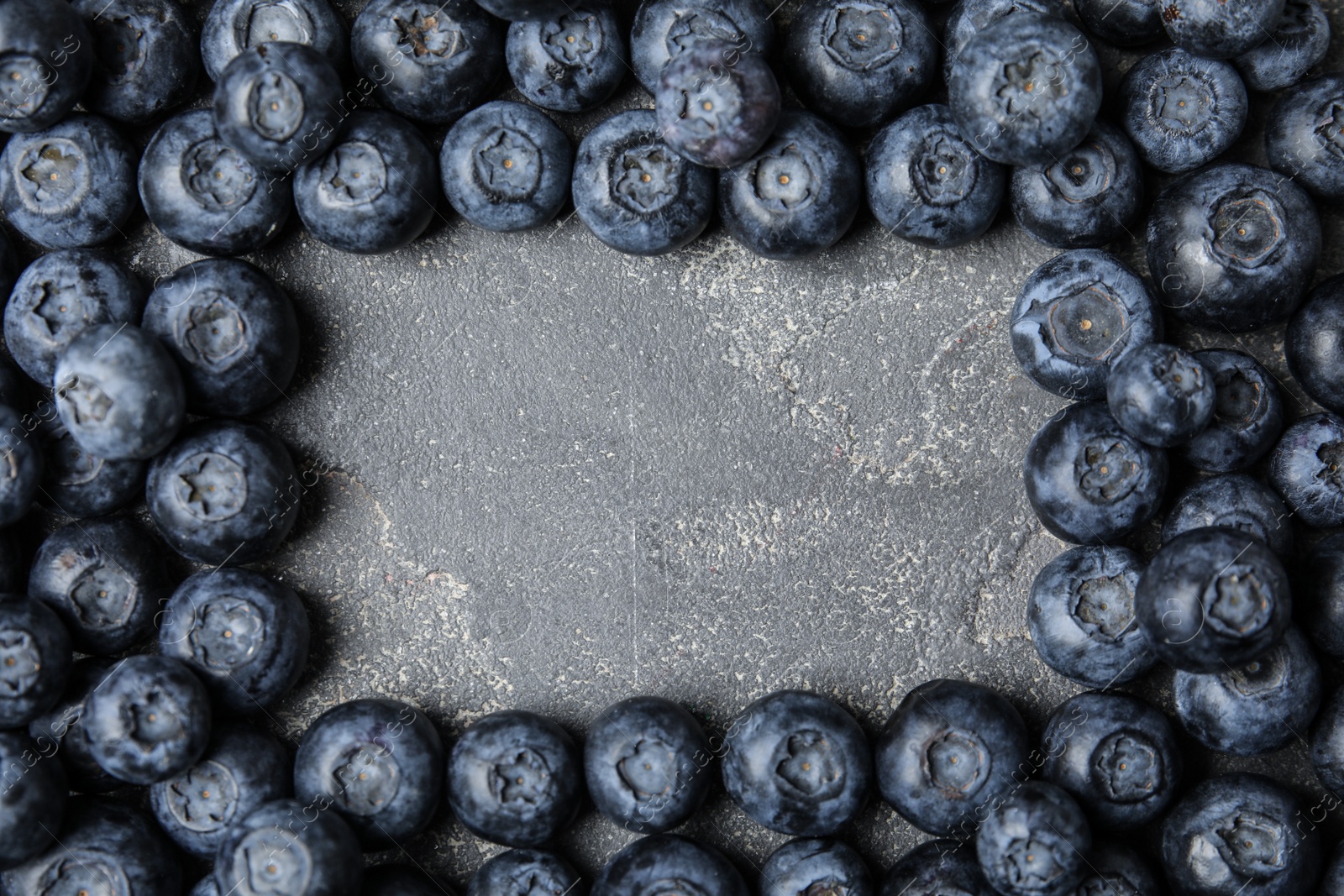 Photo of Frame made with fresh blueberries on grey table, top view. Space for text