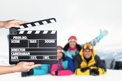 Assistant holding clapperboard and people in snowy mountains, closeup. Cinema production 
