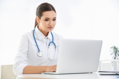 Photo of Female doctor working with laptop at table. Cardiology center