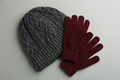 Photo of Woolen gloves and hat on light grey background, flat lay
