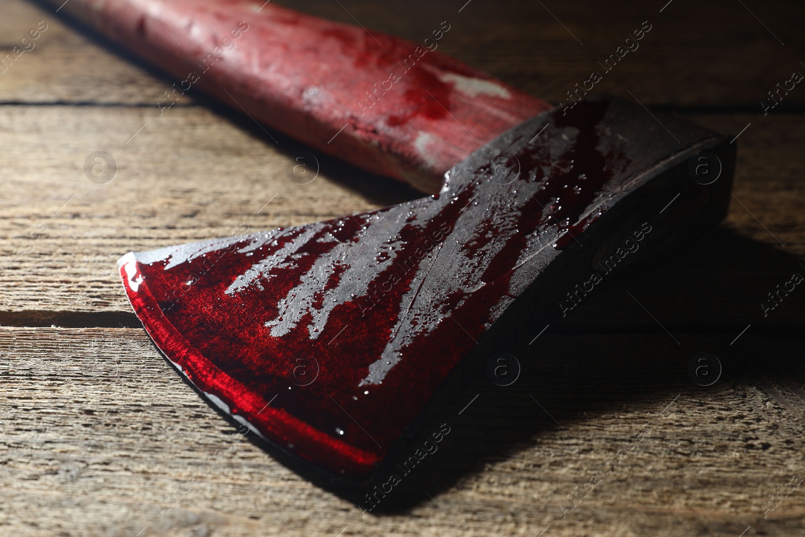 Photo of Axe with blood on wooden surface, closeup