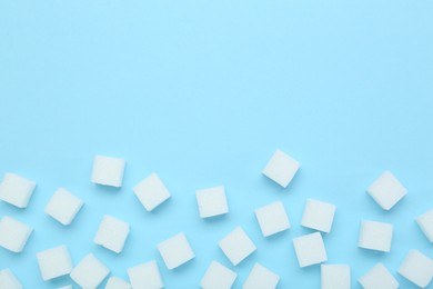 White sugar cubes on light blue background, top view. Space for text