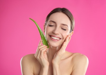 Photo of Happy young woman with aloe leaf on pink background