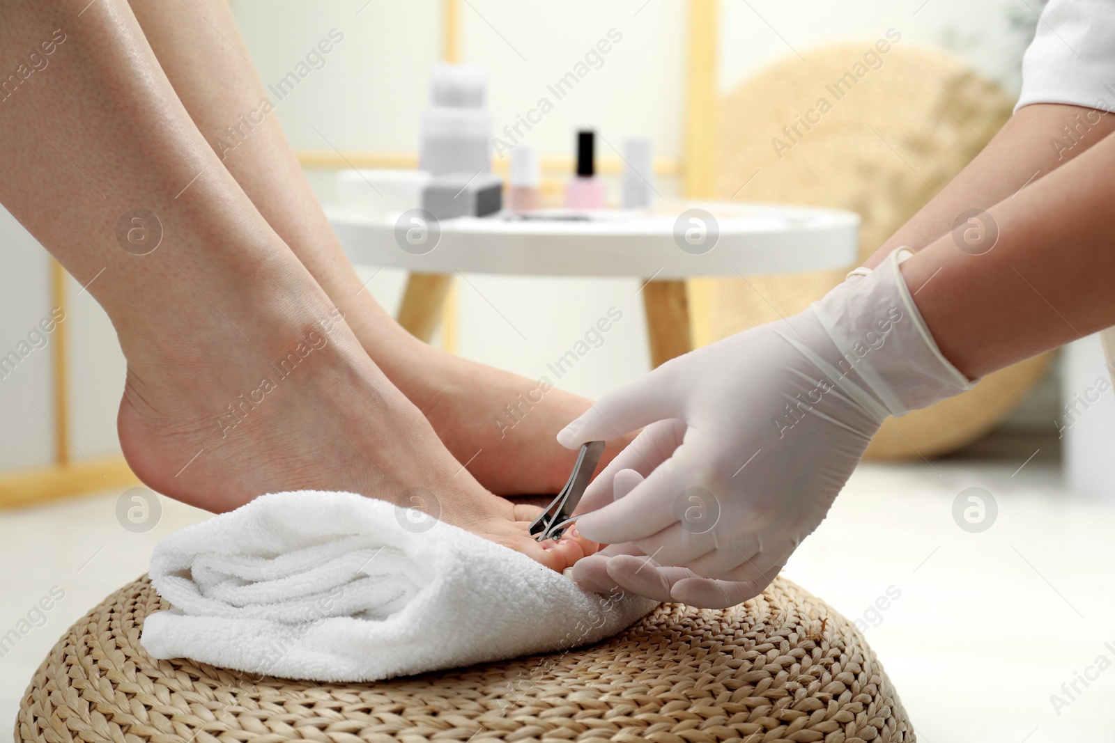 Photo of Professional pedicurist cutting client`s toenails with clipper in beauty salon, closeup