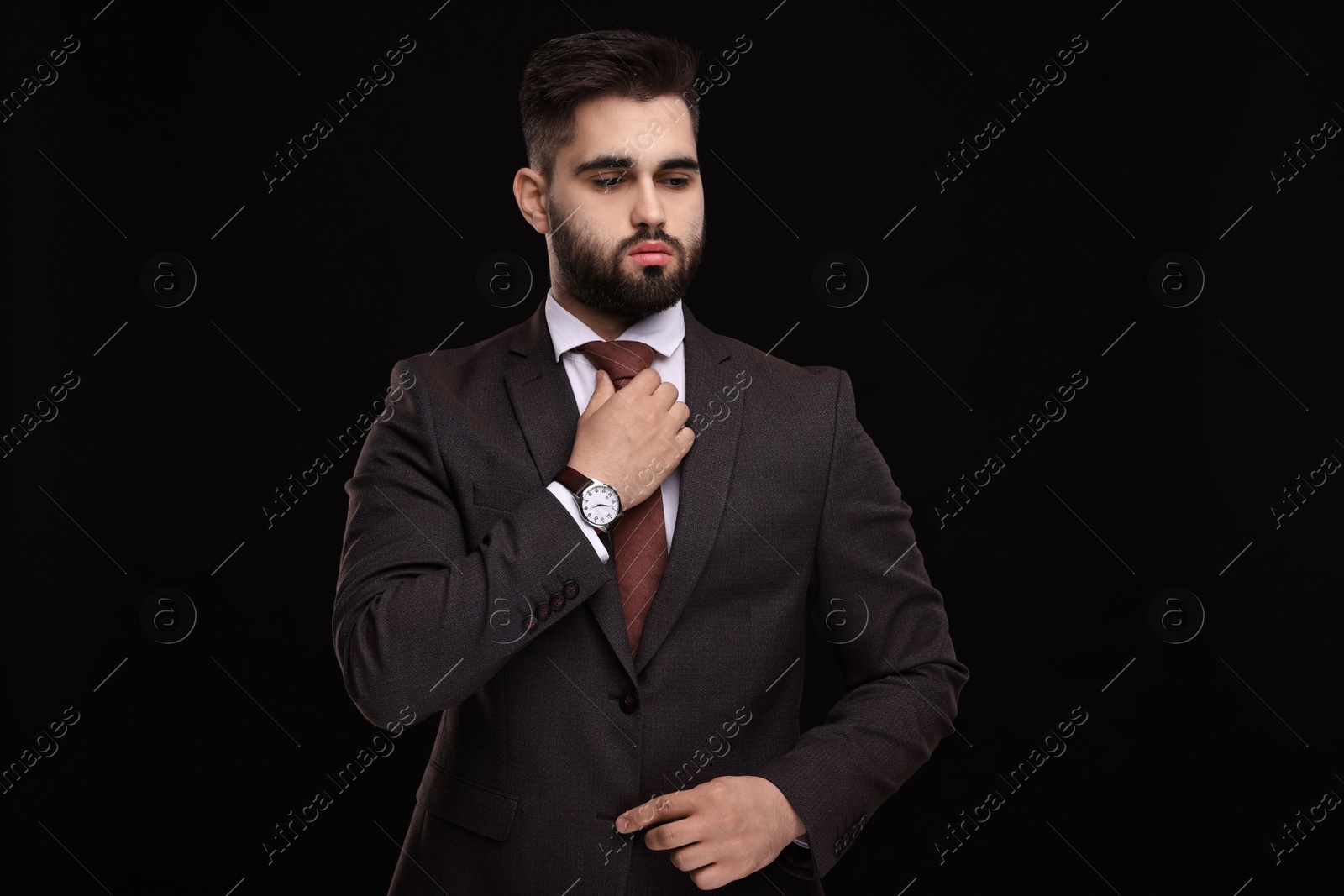 Photo of Handsome businessman in suit and necktie on black background