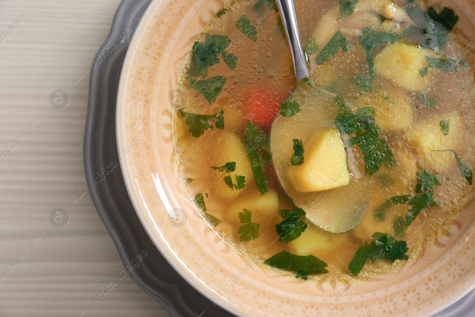 Photo of Bowl with delicious hot broth on table, top view. Cold treatment