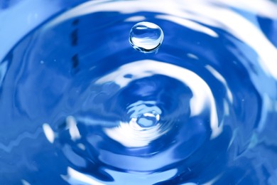 Photo of Splash of clear water with drop on blue background, closeup