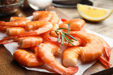 Photo of Delicious cooked shrimps with rosemary on wooden board, closeup