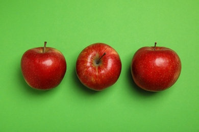 Flat lay composition with ripe juicy red apples on green background