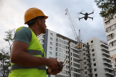 Builder operating drone with remote control at construction site. Aerial survey