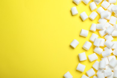 Delicious puffy marshmallows on yellow background, flat lay. Space for text