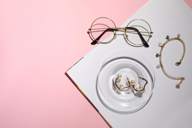 Beautiful jewelry and eyeglasses on pink background, flat lay. Space for text