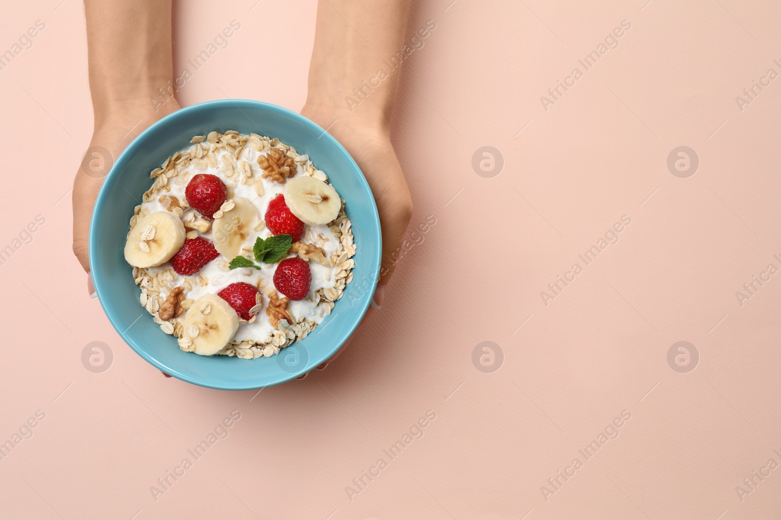 Photo of Woman holding bowl with oatmeal and fresh fruits on color background