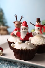 Photo of Different beautiful Christmas cupcakes on blue table with snow, closeup