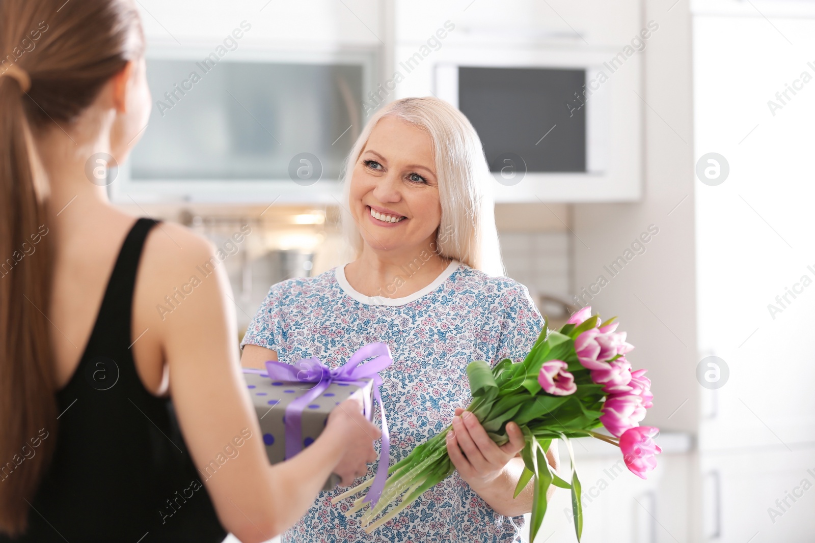 Photo of Daughter congratulating happy mature woman on Mother's Day at home