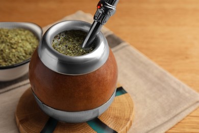 Photo of Calabash with mate tea and bombilla on wooden table, closeup. Space for text
