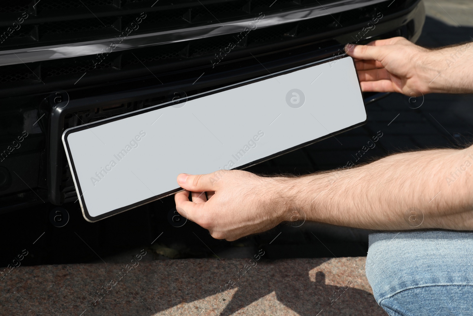 Photo of Man installing vehicle registration plate outdoors, closeup