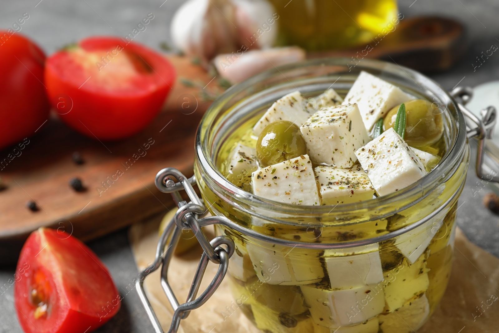 Photo of Composition with pickled feta cheese in jar on grey table, closeup