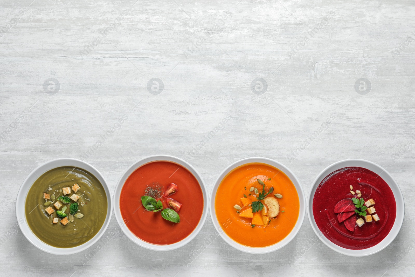 Photo of Various soups in bowls and space for text on white background, top view. Healthy food