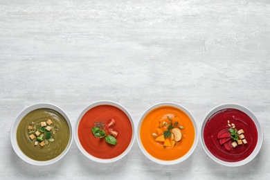 Various soups in bowls and space for text on white background, top view. Healthy food