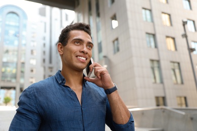 Photo of Portrait of handsome young African-American man talking on mobile phone outdoors. Space for text