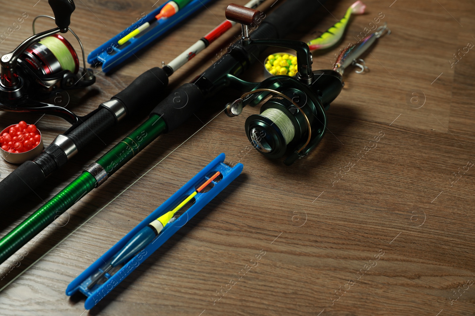 Photo of Spinning rods and fishing tackle on wooden background, closeup