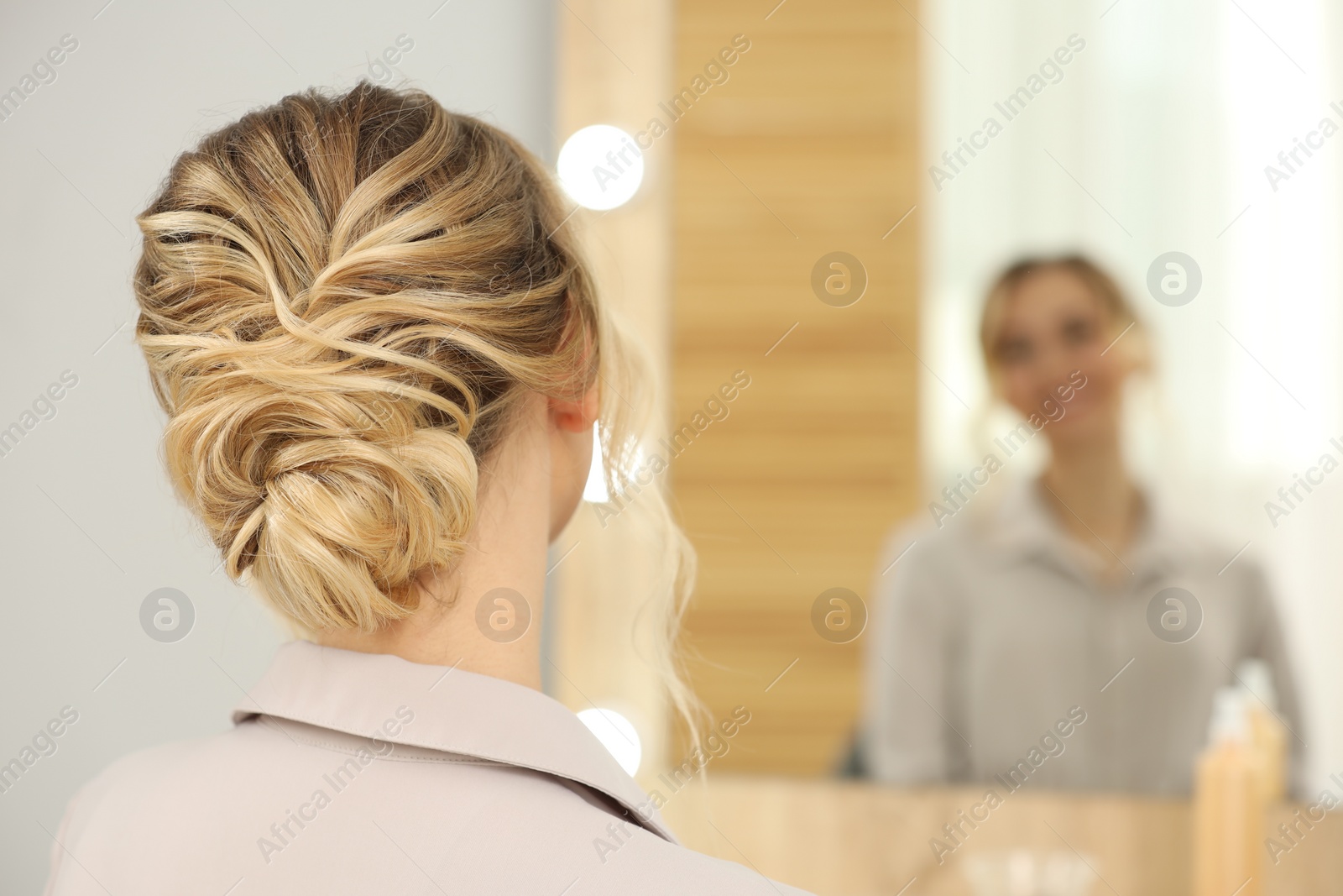 Photo of Woman with beautiful hair style looking at mirror indoors. Space for text