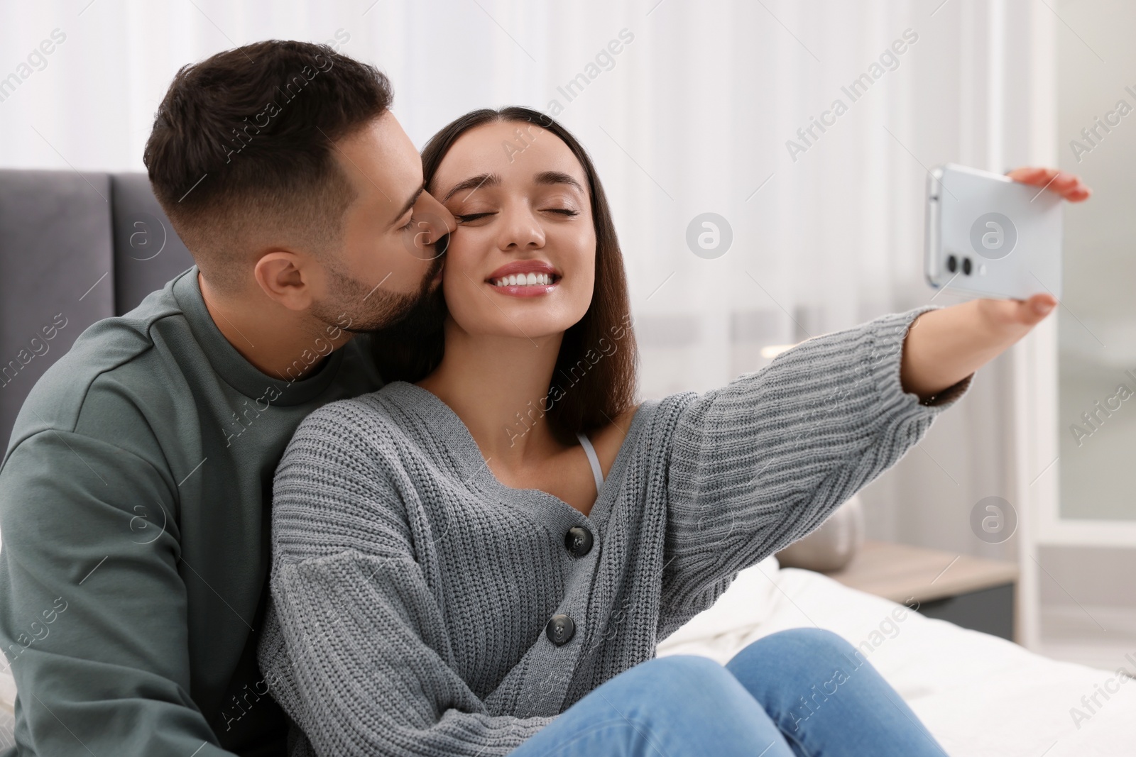 Photo of Happy young couple taking selfie in bedroom