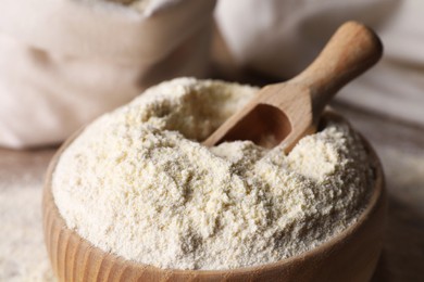 Wooden bowl with quinoa flour and scoop on table, closeup