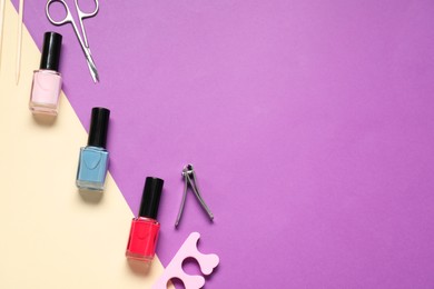 Photo of Nail polishes and set of pedicure tools on color background, flat lay. Space for text