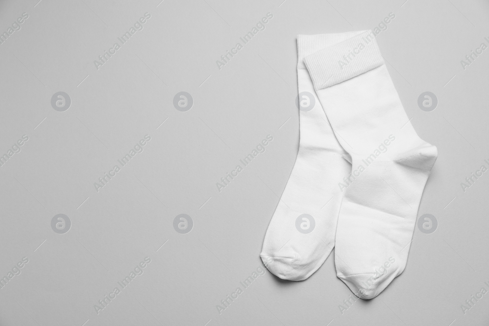 Photo of White socks on light grey background, flat lay. Space for text
