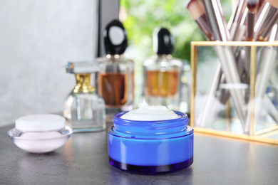 Photo of Open jar of cream on grey dressing table indoors