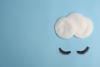 Photo of Cotton pads for makeup removal and false eyelashes on light blue background, flat lay. Space for text