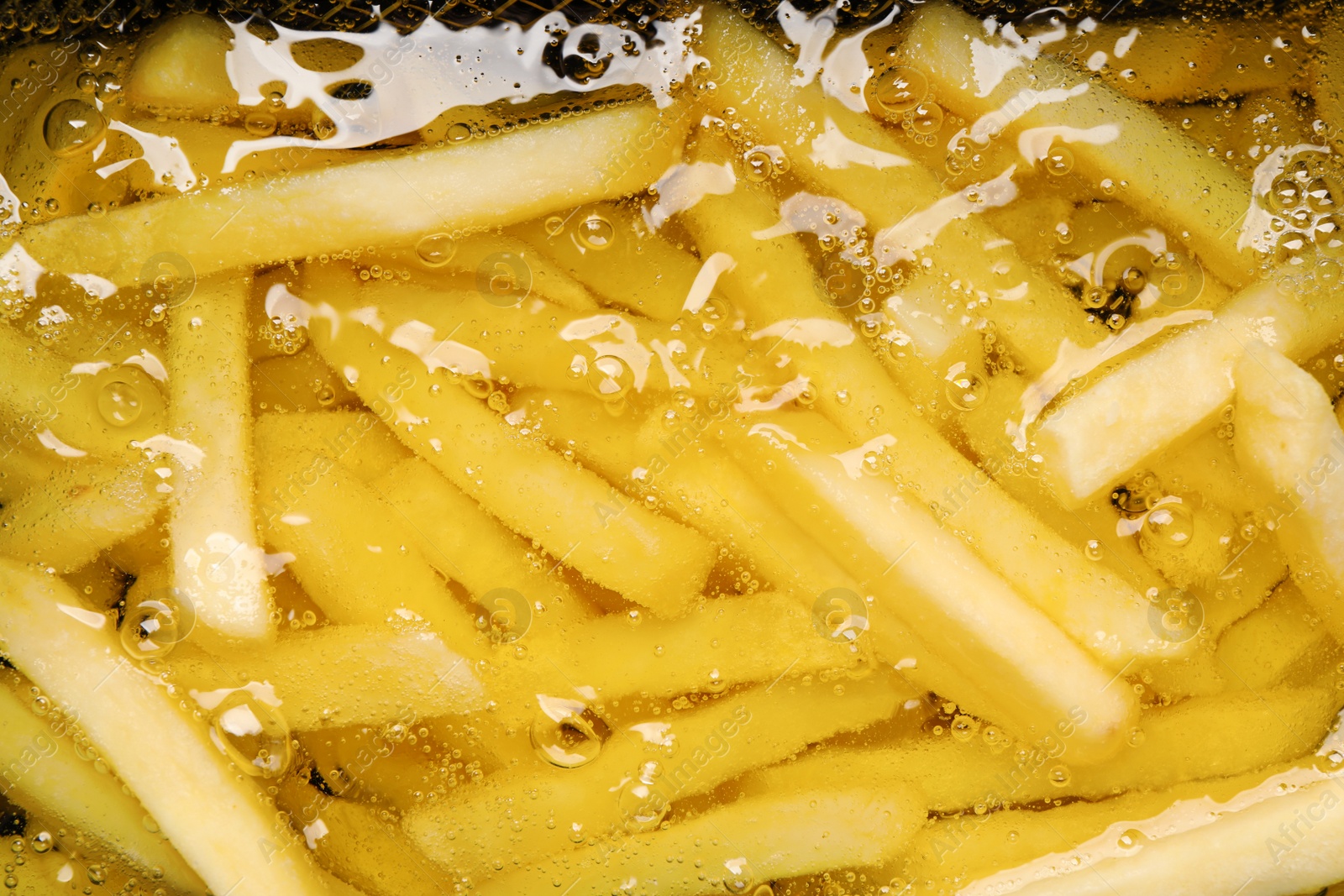 Photo of Cooking delicious french fries in hot oil, closeup